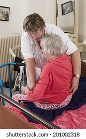 Care Giver Helping Elderly Woman To Dress At Home