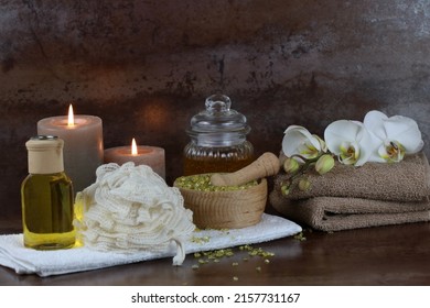 Care items for wellness treatments with aromatic oils, towel, orchid blossom and a scented candle.