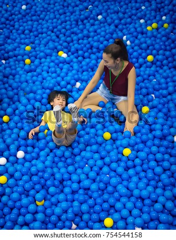 Care Taker Plays with a Boy in a Pool of Plastic Balls