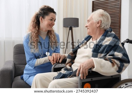 Care worker checking senior woman's pulse in wheelchair indoors