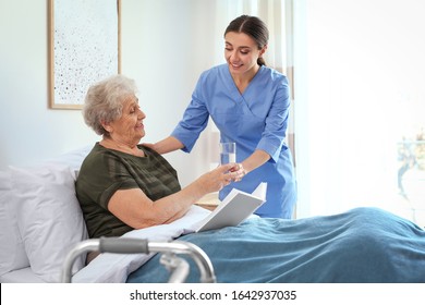 Care worker giving water to elderly woman in geriatric hospice - Powered by Shutterstock