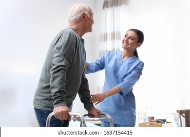 Care worker helping elderly man with walker in geriatric hospice - Powered by Shutterstock