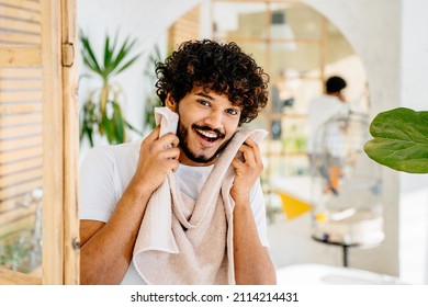 Care for your beard concept. Overjoyed Handsome young man wiping face with white towel after shower or shaving, standing in bathroom. - Powered by Shutterstock