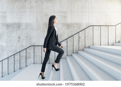 Career success concept with young woman climbs the stairs to the light in abstract building with stylish wall and light stairway