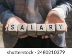 A career woman in office attire holding a piece of wood with the word salary written on it, symbolizing the concept of career and salary