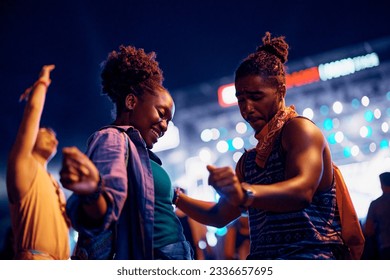 Carefree African American couple of festival goers dancing at summer music concert at night.  - Powered by Shutterstock