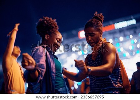Carefree African American couple of festival goers dancing at summer music concert at night.  商業照片 © 
