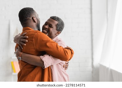 Carefree african american man hugging adult son at home - Powered by Shutterstock