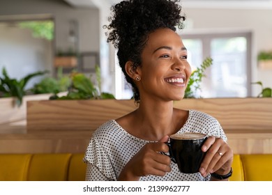 Carefree african american woman sitting in cafeteria drinking coffee while looking away. Black young woman drinking tea while thinking. Smiling girl relaxing and thinking while drinking cappuccino. - Powered by Shutterstock