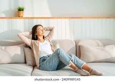 Carefree Asian woman relaxing and sitting on a sofa at home in the morning - Powered by Shutterstock