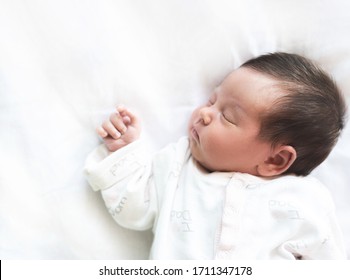 Carefree baby sleeps after breastfeeding.Baby is fed up and calm. White background, Copy space.  Care, peace of mind, safety, peaceful childhood dream, peaceful baby's dream concept