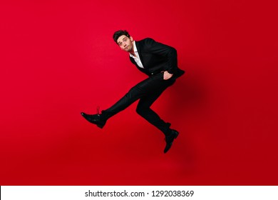 Carefree Boy In Black Suit Dancing. Jumping Man Looking At Camera.