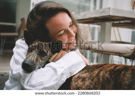 Carefree Caucasian female cynologist resting and hug during leisure pastime with mongrel puppy dog from shelter, happy woman with pet enjoying weekend for communication with fluffy best friend Сток-фото © 