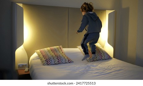 Carefree child bounding up and down in hotel bed during vacation travel - Powered by Shutterstock