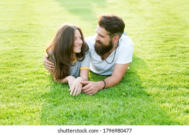 Carefree couple enjoying sunny day relaxing on green meadow, love from first sight concept.