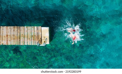 A carefree couple jumps into the azure sea. Aerial view. A vacation in the summertime. Young and energetic people dive into the water together. A fun vacation at the sea together. - Shutterstock ID 2192283199