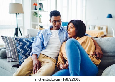 Carefree Dark Skinned Marriage Enjoying Home Recreation During Weekend In Cozy Apartment With Loft Interior, African American Male And Female 20s Hugging At Comfortable Couch In Living Room