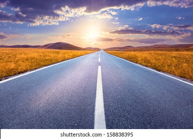 Carefree Driving On An Empty Road At Sunset