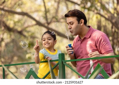 Carefree father and daughter having fun playing with bubble at park - Powered by Shutterstock