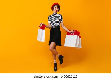 Carefree French Lady Posing After Shopping. Adorable Woman In Red Beret Holding Store Bags.