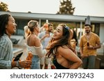 Carefree friends having fun while dancing during summer day on a party by the swimming pool. Focus on a brunette woman