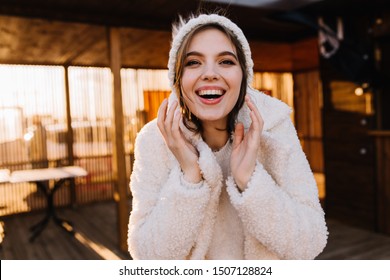 Carefree Girl In Winter Outfit Smiling At Camera. Indoor Shot Of Sensual Brunette Woman In Knitted Hat.