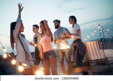 Carefree group of happy friends enjoying party on rooftop terrace