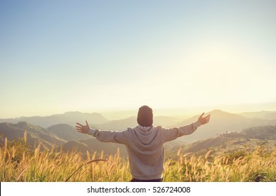 Carefree Happy Man Enjoying Nature on grass meadow on top of mountain cliff with sunrise. Beauty Outdoor. Freedom concept. Sunbeams. Enjoyment. copy space. - Powered by Shutterstock