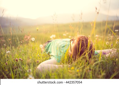Carefree happy man lying on green grass meadow in mountains enjoying the sun on his face.Enjoying nature sunset.Freedom.Enjoyment.Relaxing in mountains at sunrise.Sunshine.Daydreaming