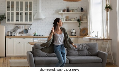 Carefree happy single young attractive woman dancing alone in modern kitchen interior, independent active lady having fun at clean home listening music enjoying freedom weekend time lifestyle at home - Powered by Shutterstock
