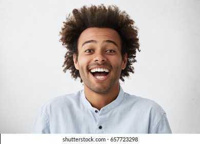 Carefree Joyful Handsome Afro American Man With Bushy Hairstyle And Bristle Having Shining Eyes Opening His Mouth With Joy Bursting Into Laughing. Positive Human Expressions, Emotions And Feelings