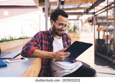 Carefree Latinos Male Student In Classic Glasses Spending Time For Analyzing Organization Plan, Young Hipster Guy In Optical Spectacles For Provide Eyes Correction Writing Ideas During Paperwork