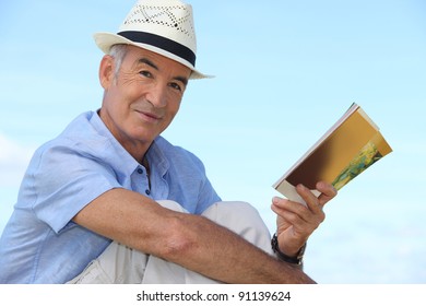 Carefree Man Reading A Book Outside