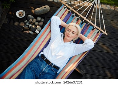 Carefree mature woman sleeping in hammock at her house patio - Powered by Shutterstock