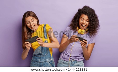 Carefree outgoing teenage gamers play online games, win first place or gain highest score, tilt from each other, look with passion, being addicted gamblers, entertained with awesome application