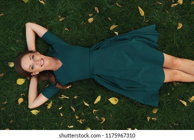 carefree pretty woman lies on a fresh green grass and smiling. Top view