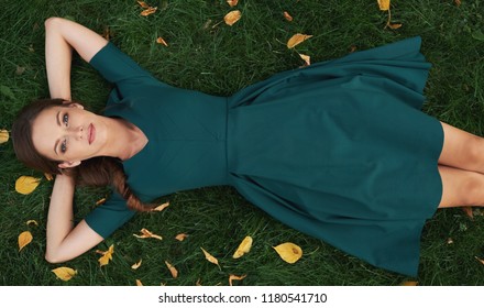 carefree pretty woman is lying on green grass in the park. Top view