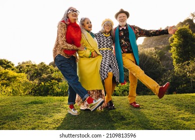 Carefree Senior Citizens Having Fun While Standing Together In A Park. Group Of Cheerful Senior Friends Wearing Colourful Casual Clothing. Happy Elderly People Enjoying Life After Retirement.