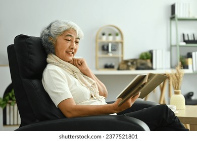 Carefree senior man in casual clothes sitting armchair and reading book.
