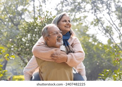 Carefree senior man piggybacking playful wife in park - Powered by Shutterstock