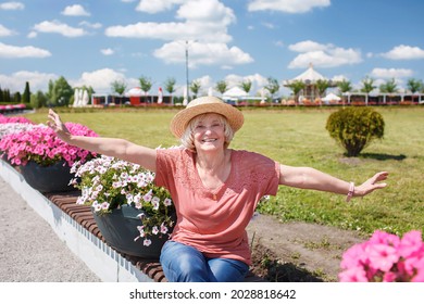 Carefree Senior Woman In Straw Hat Walking In The Flower Park At Sunny Day, Mental And Physical Health, Age And Nature Beauty, Baby Boomer Generation, Solo Traveler, Summer Lifestyle