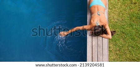 Carefree summer splashing. Shot of a beautiful young woman relaxing by a swimming pool.