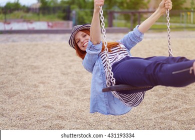 Carefree trendy young woman on a swing leaning back and grinning at the camera with a vivacious smile - Powered by Shutterstock