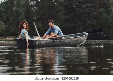 Carefree weekend. Beautiful young couple enjoying romantic date while rowing a boat
