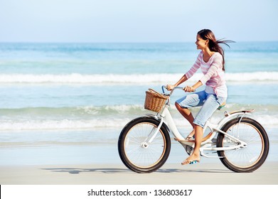 carefree woman with bicycle riding on beach sand having fun and smiling - Powered by Shutterstock