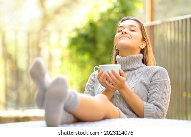 Carefree Woman Breathing Fresh Air Relaxing Drinking Coffee In A Garden At Home In Winter 