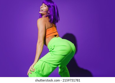 Carefree Woman Dancer Wearing Colorful Sportswear Twerking Against Purple Background