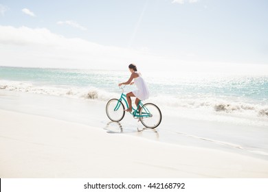 Carefree Woman Going On A Bike Ride On The Beach