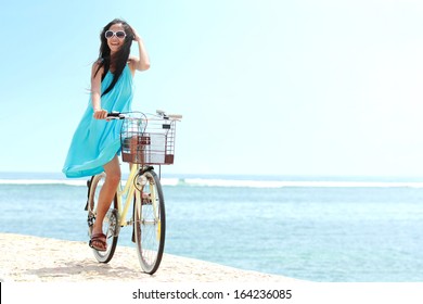 carefree woman having fun and smiling riding bicycle at the beach - Powered by Shutterstock