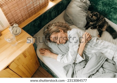 Carefree woman sleeping in bed early in the morning.